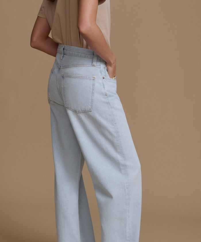 Light blue jeans worn by a person on a brown background