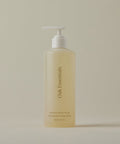 A translucent bottle with a white pump, labeled Awaken Body Wash, is displayed against a plain, light beige background.