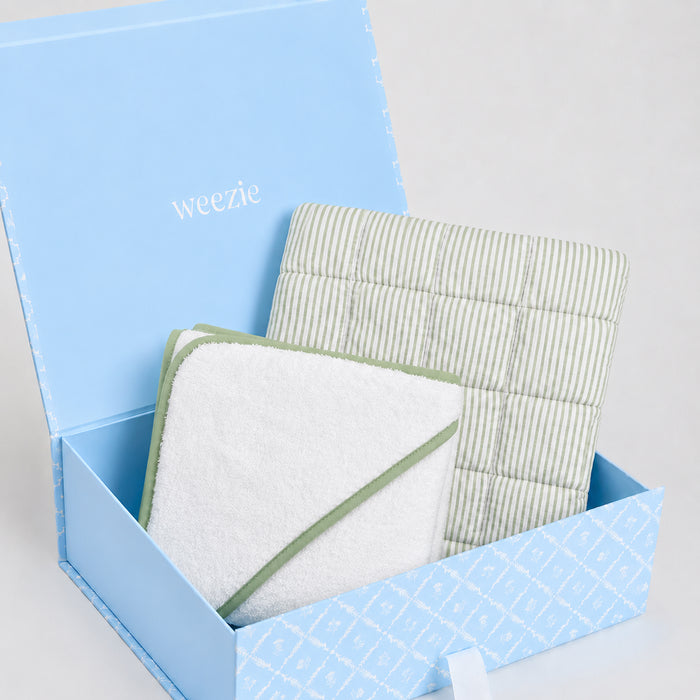 Blue Weezie gift box with a green striped baby mat and a white hooded towel with matcha green trim.