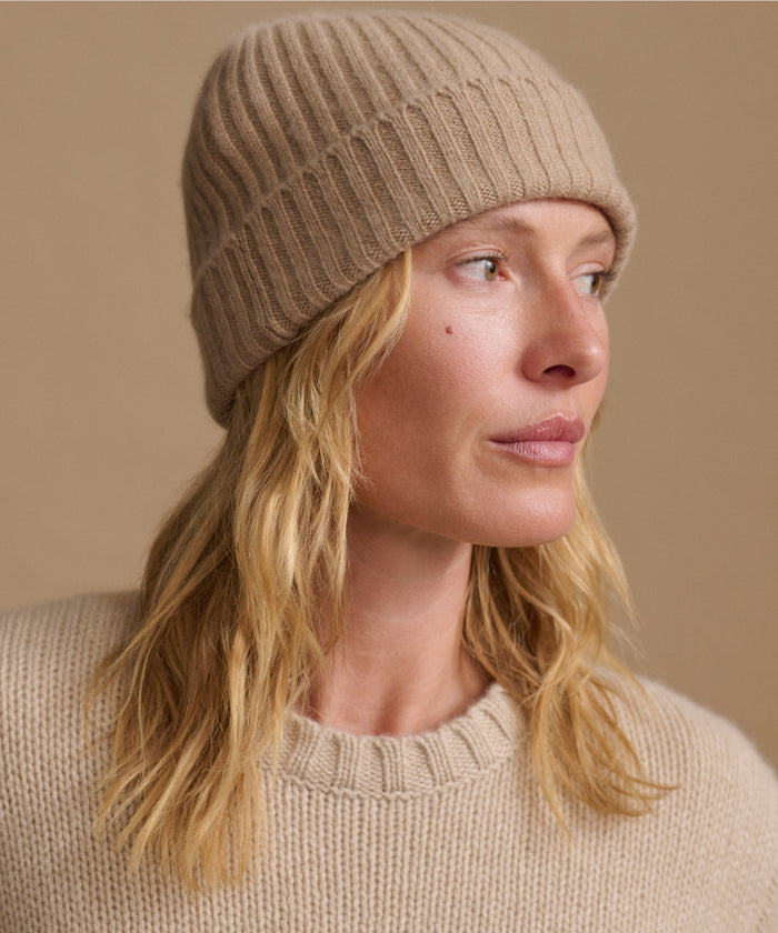Woman wearing an oatmeal color cashmere sweater with a matching ribbed beanie.