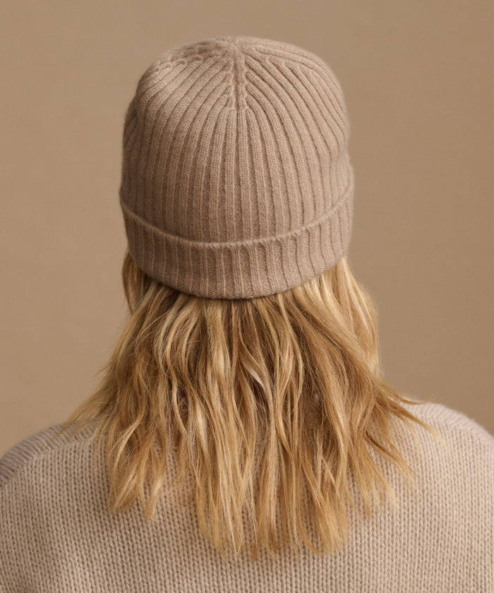 Woman wearing an oatmeal color cashmere sweater with a matching ribbed beanie.
