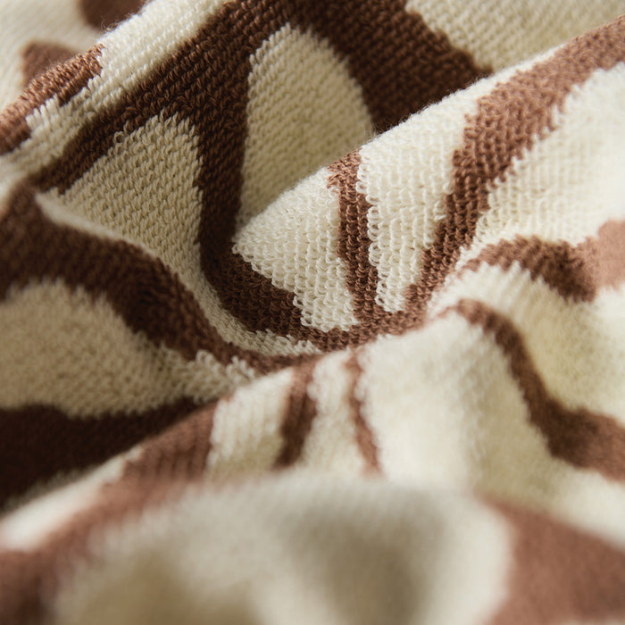 Cotton towel in cream and brown with textured pattern, close-up of absorbent surface.