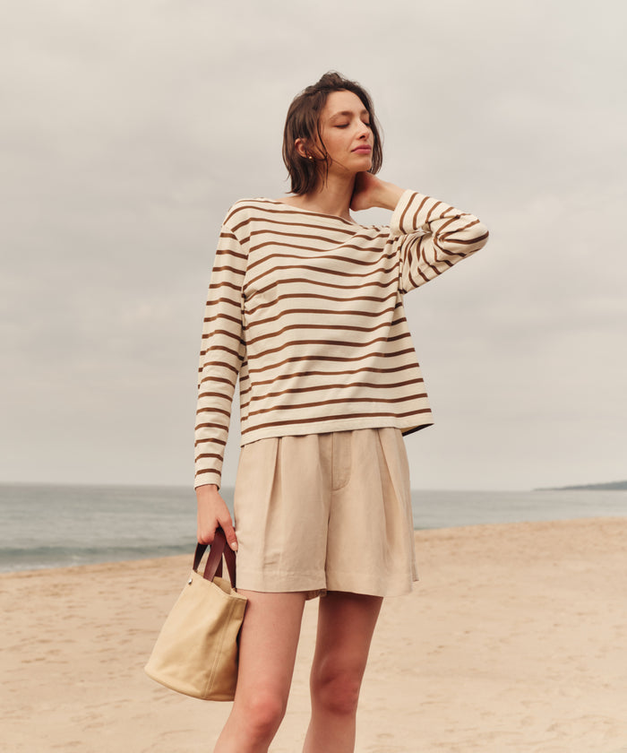 Woman in a striped shirt and shorts standing on a beach.