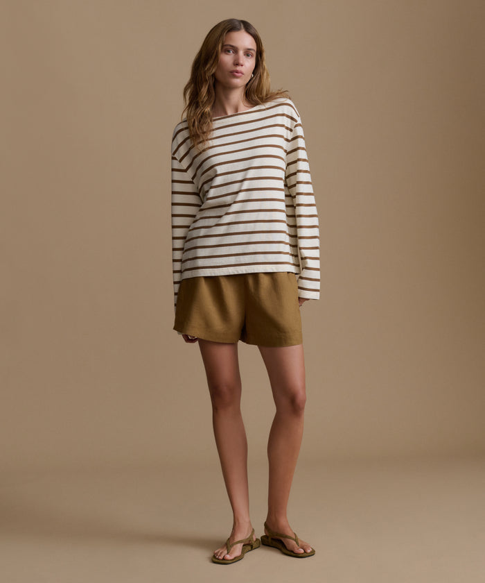Woman wearing a striped shirt and shorts on a brown background