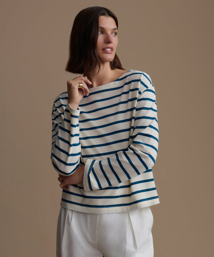 Woman wearing a blue and white striped shirt against a beige background