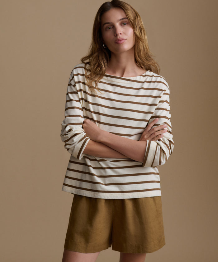 Woman wearing a striped shirt and shorts against a beige background