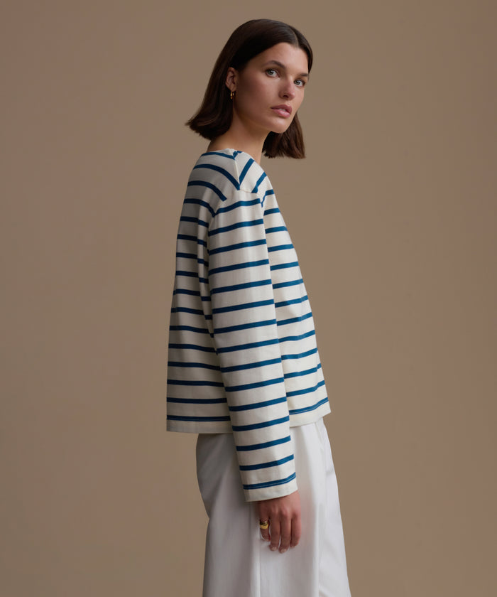 Woman wearing a blue and white striped shirt against a beige background