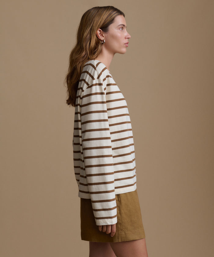 Woman wearing a striped shirt and shorts against a beige background
