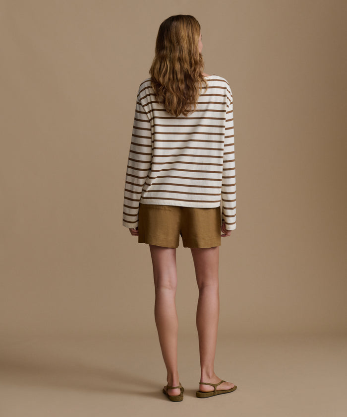 Woman wearing a striped shirt and shorts against a beige background