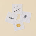 Four white cocktail napkins with Halloween embroidery: bats, pumpkin, boo, and spiderweb.