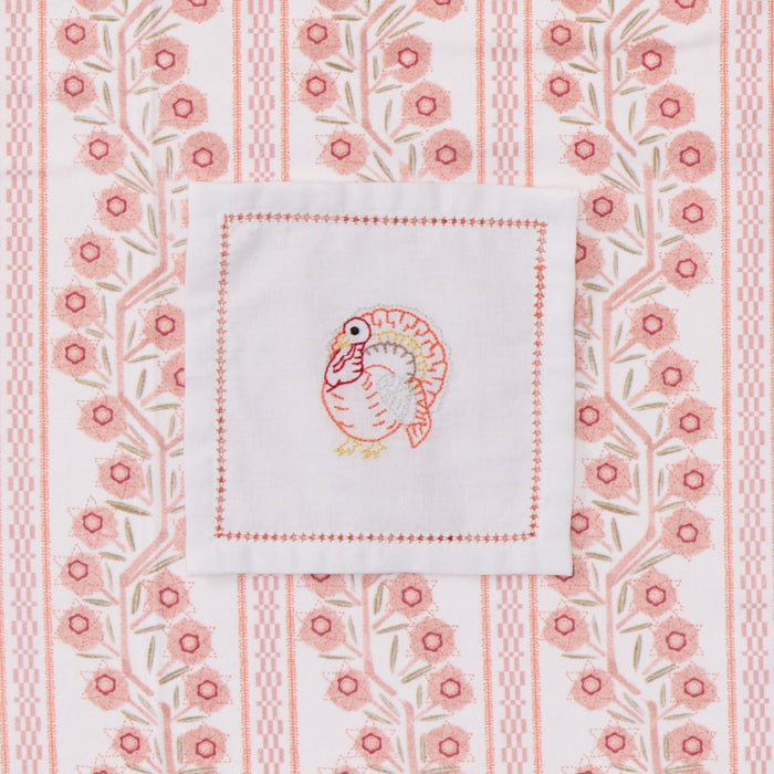 White cocktail napkin with turkey embroidery.