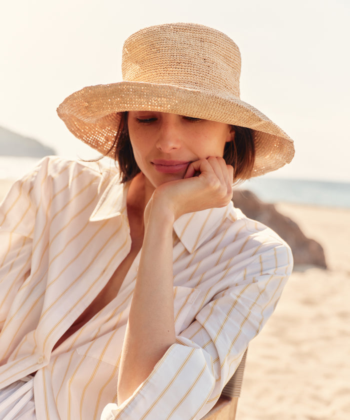Woman wearing a straw hat and white striped shirt on a beach