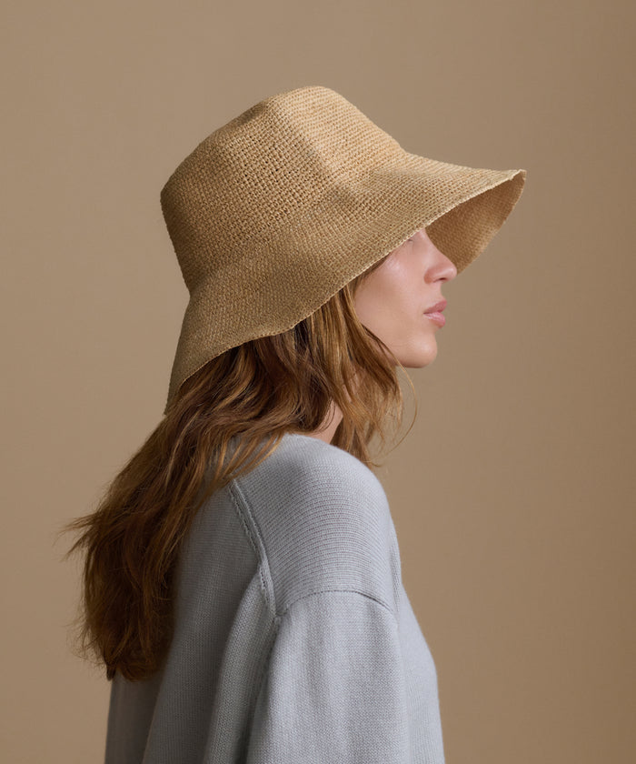 Woman wearing a beige sun hat against a brown background