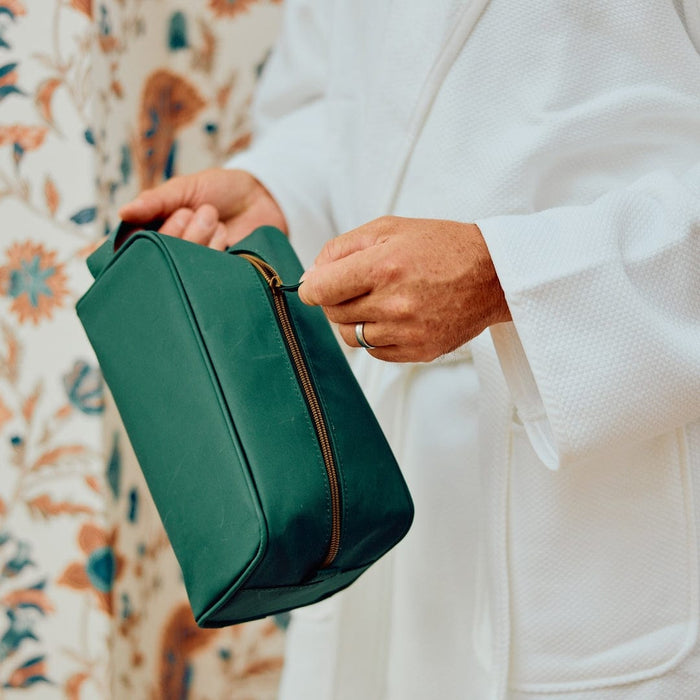 photo of a man in white robe, holding the Dopp Kit in Hunter Green