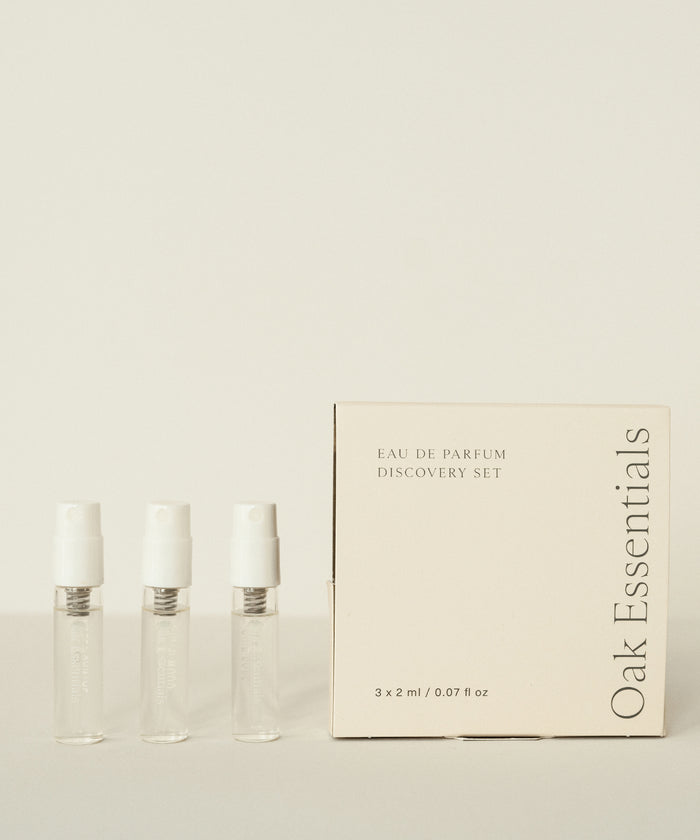 Three small clear perfume vials stand beside a cream-colored box labeled Eau De Parfum Discovery Set, ideal for exploring signature scents, all displayed against a light background.