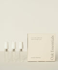 Three small clear perfume vials stand beside a cream-colored box labeled Eau De Parfum Discovery Set, ideal for exploring signature scents, all displayed against a light background.
