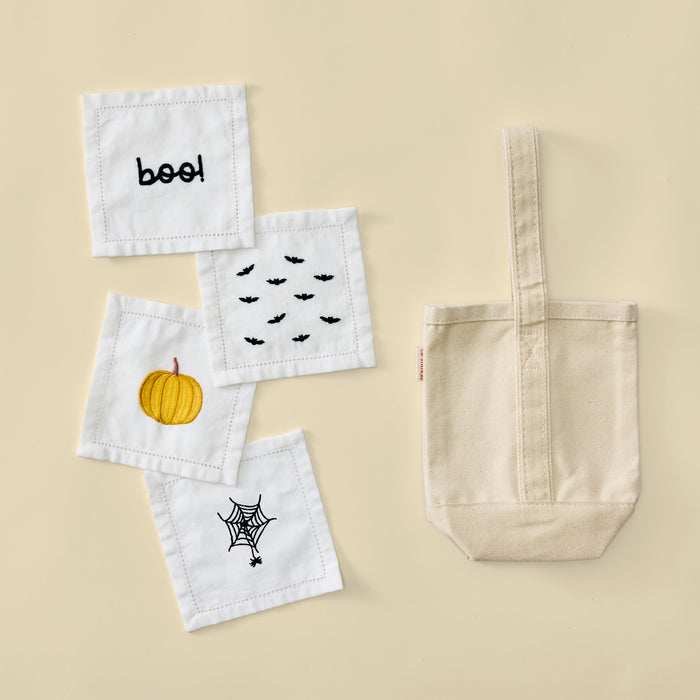 Plain cream canvas wine tote bag next to four white Halloween embroidered cocktail napkins.
