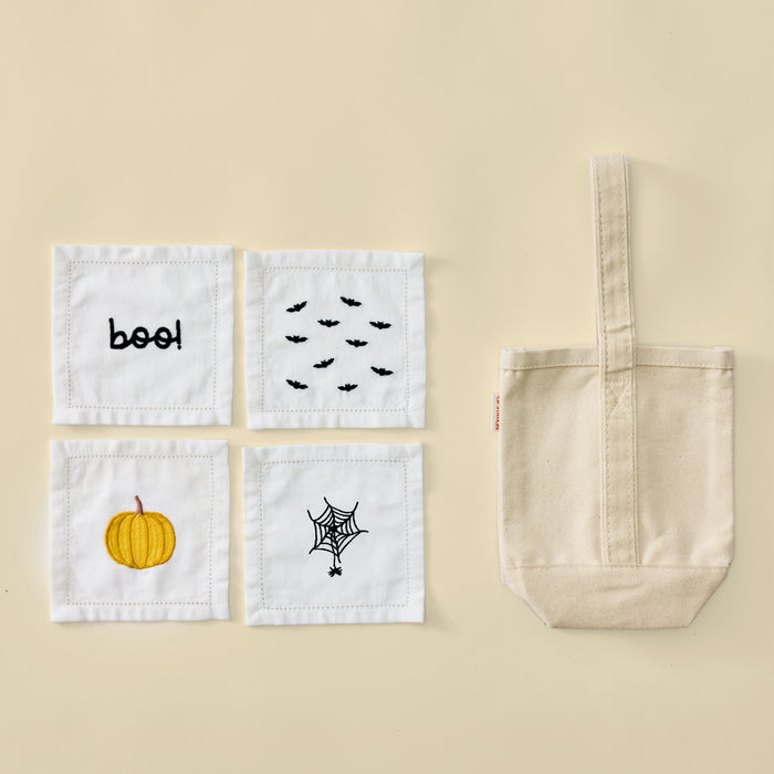 Plain cream canvas wine tote bag next to four white Halloween embroidered cocktail napkins.