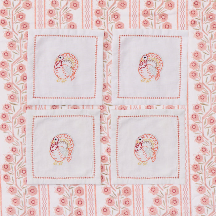Four white turkey embroidered cocktail napkins.