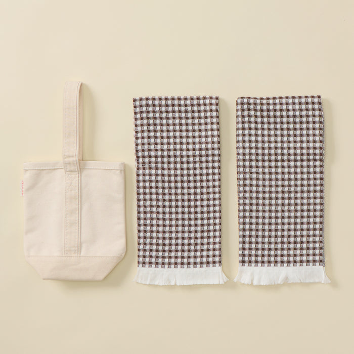 A Hostess Set featuring a plain cream canvas tote bag and two brown and cream gingham towels with fringed edges.