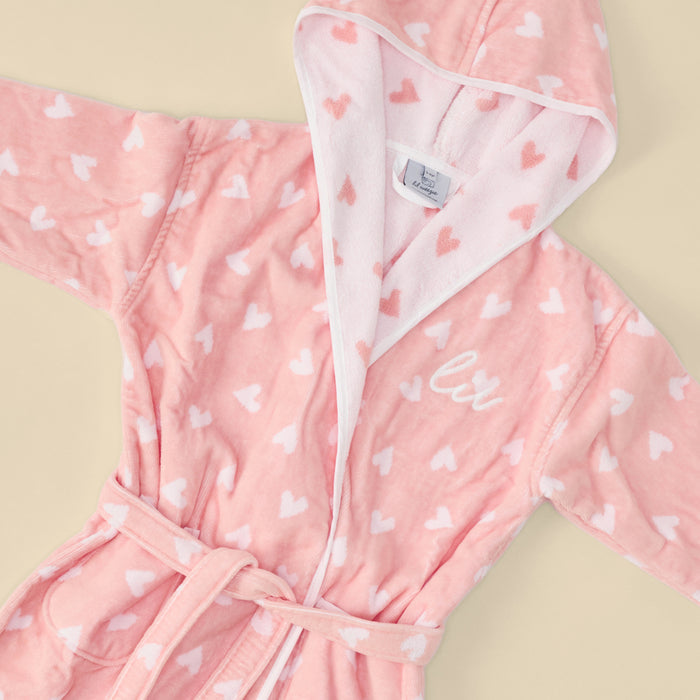 A fluffy coral pink bathrobe with white hearts and "lil" embroidery.