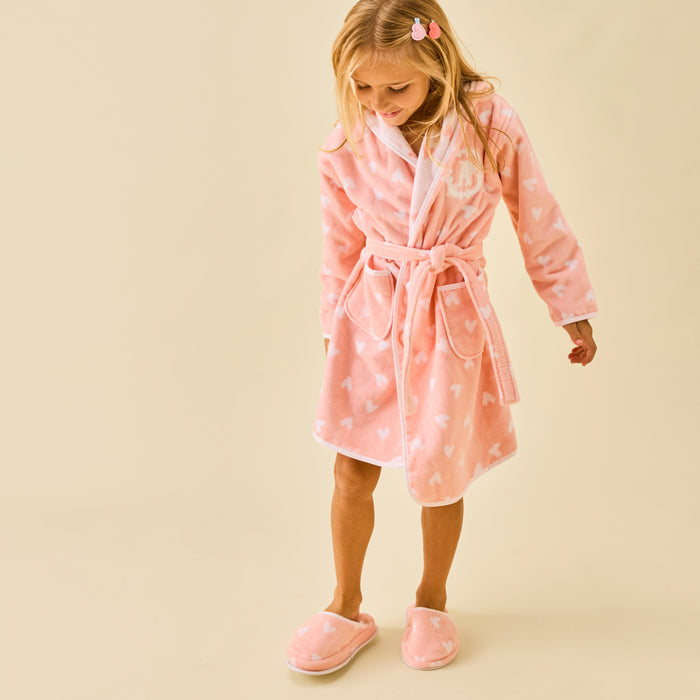 Girl wearing fluffy coral pink slippers with white hearts and a matching robe.