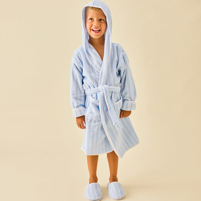 A boy wearing soft terry slippers and matching bathrobes in light blue stripes.
