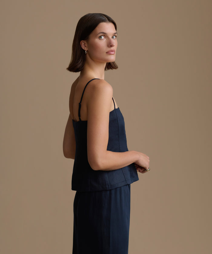 Woman wearing a navy kinney cami and pants against a beige background
