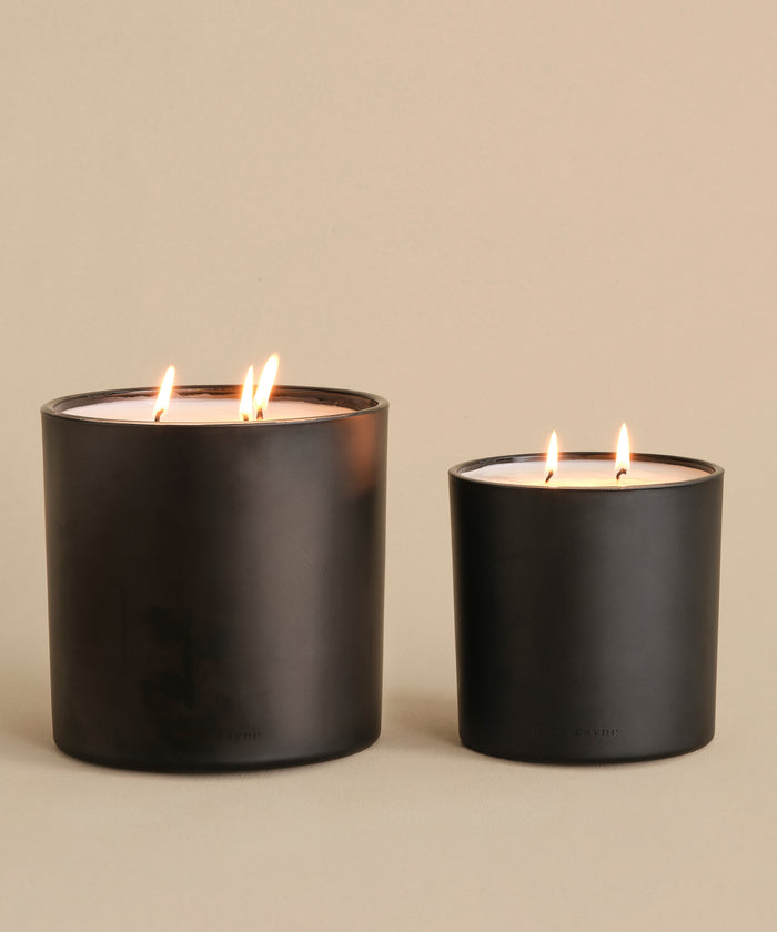 Two twin-flame black matte candles, including the 28oz Large Cedar Glass Candle inspired by Oprah’s Favorite Things, are lit and placed side by side on a neutral background.