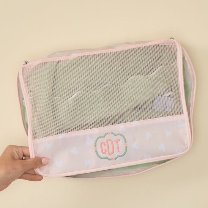Personalized Tossed Pink Hearts packing cube featuring an embroidered 'CDT' monogram, set against a light background.