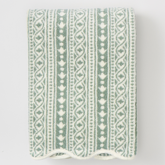 A folded cotton towel with a vertical knit pattern in sage green and white, shown against a plain light gray background.