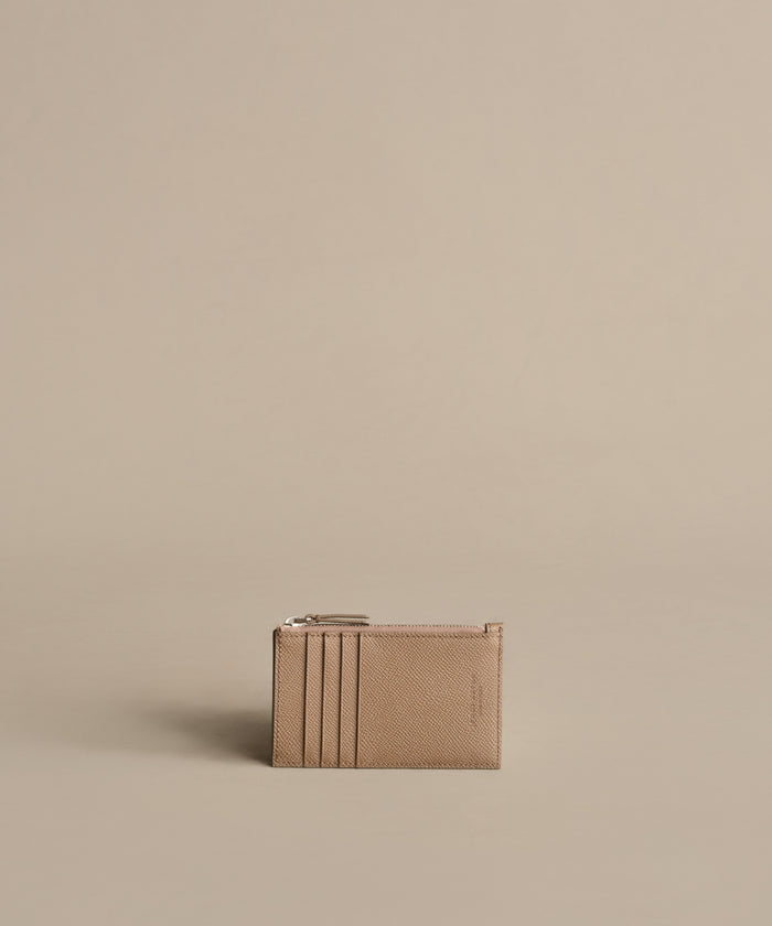 A compact Leather Card Holder in taupe with multiple card slots and a top zipper, ideal for light travel. Shown against a plain beige background.