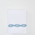 Folded white bath towel with a light blue wavy embroidered trim featuring green oval motifs.