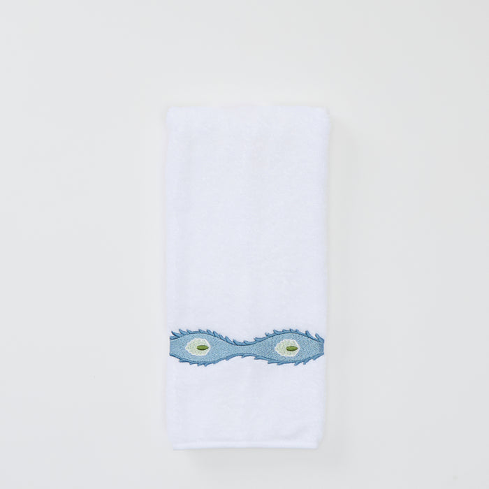 A white Weezie hand towel with wavy blue Lee Jofa Marciana embroidery on a white background.