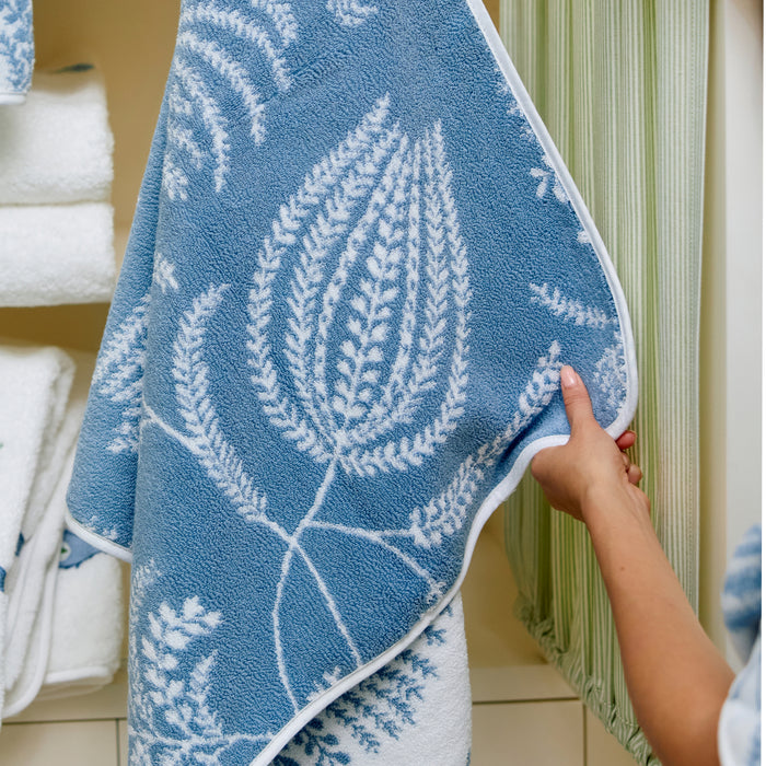 Plush white bath towel with a light blue floral Palmero pattern and a reversible dark blue pattern