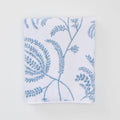 A folded white bath towel featuring a delicate light blue Palmero botanical pattern