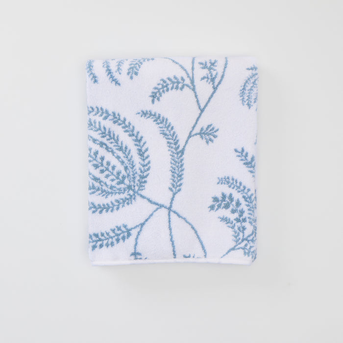 A folded white bath towel with a light blue Palmero pattern and custom embroidery.
