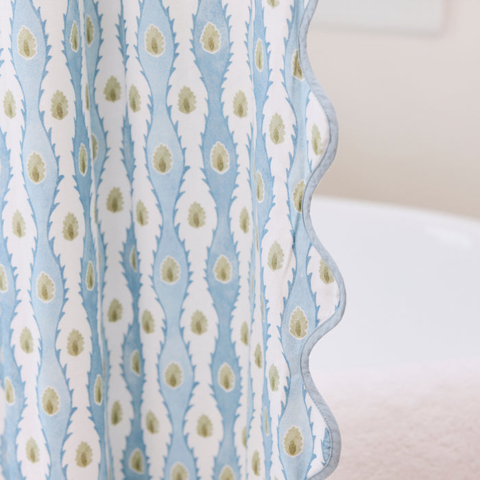 Close-up of shower curtain edge showing blue scalloped trim and blue-white floral pattern.