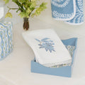 Light blue lacquered tray displaying a white powder bath towel with blue floral embroidery.