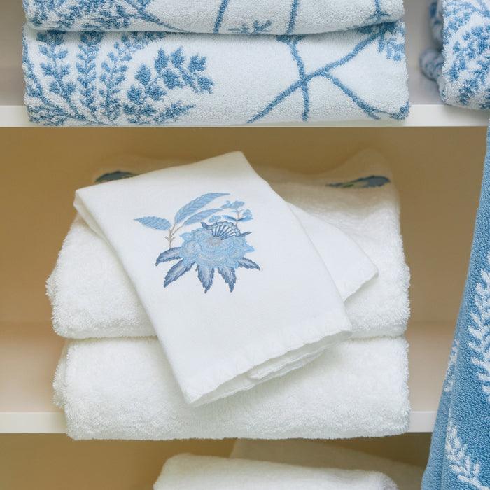 Three stacked white towels, top of which features blue Davenport floral embroidery
