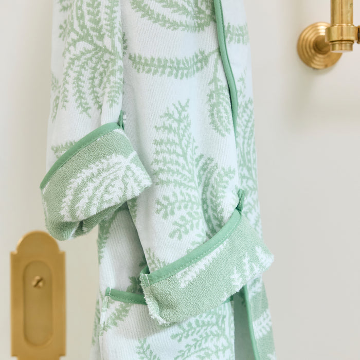 Close-up of a hanging sage green and white botanical plush robe, focusing on the folded cuff.
