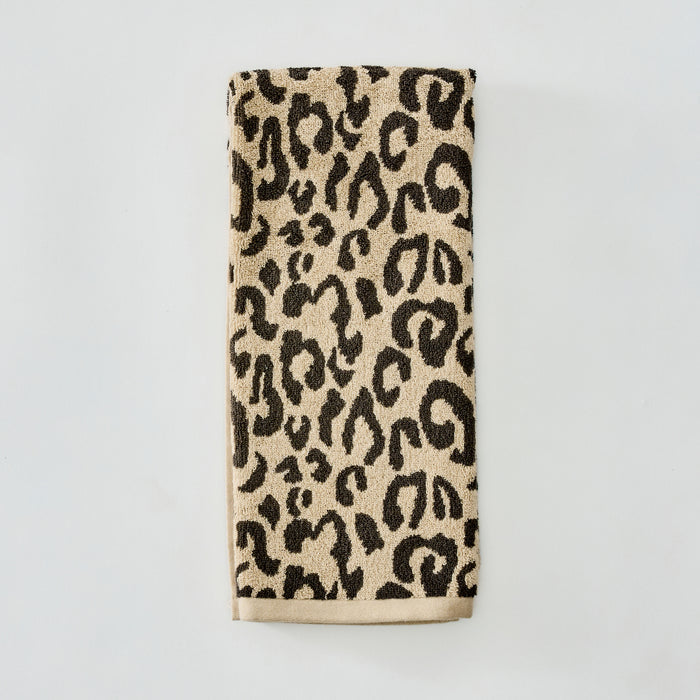 A folded beige towel with a black leopard print pattern and a solid beige bottom border, displayed against a clean white background.