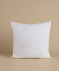 A white linen pillow against a beige background.