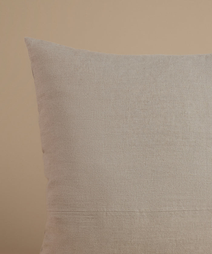A natural linen pillow against a beige background.