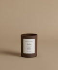 A glass candle by Jenni Kayne in the scent Malibu against a beige background.