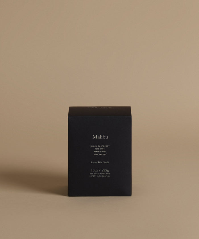 A candle box with the scent Malibu across the front against a beige background.