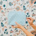 A photo of a hand opening the small patterned toiletry bag archive in Blue Trellis