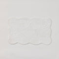 A plush white bath rug with scalloped edges.