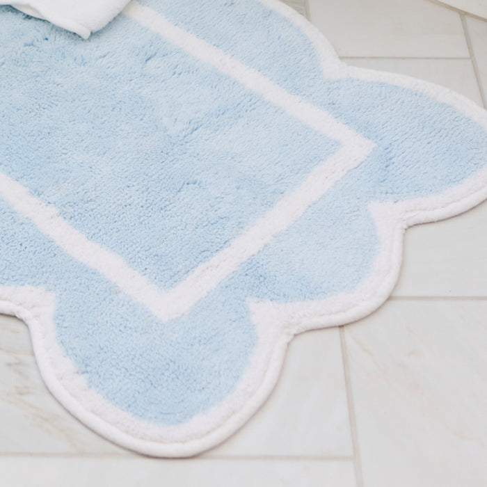 Light blue scalloped bath rug on a bathroom floor