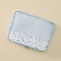 A rectangular mesh zippered travel organizer pouch with a white floral print border and a light blue interior, shown on a solid beige background.
